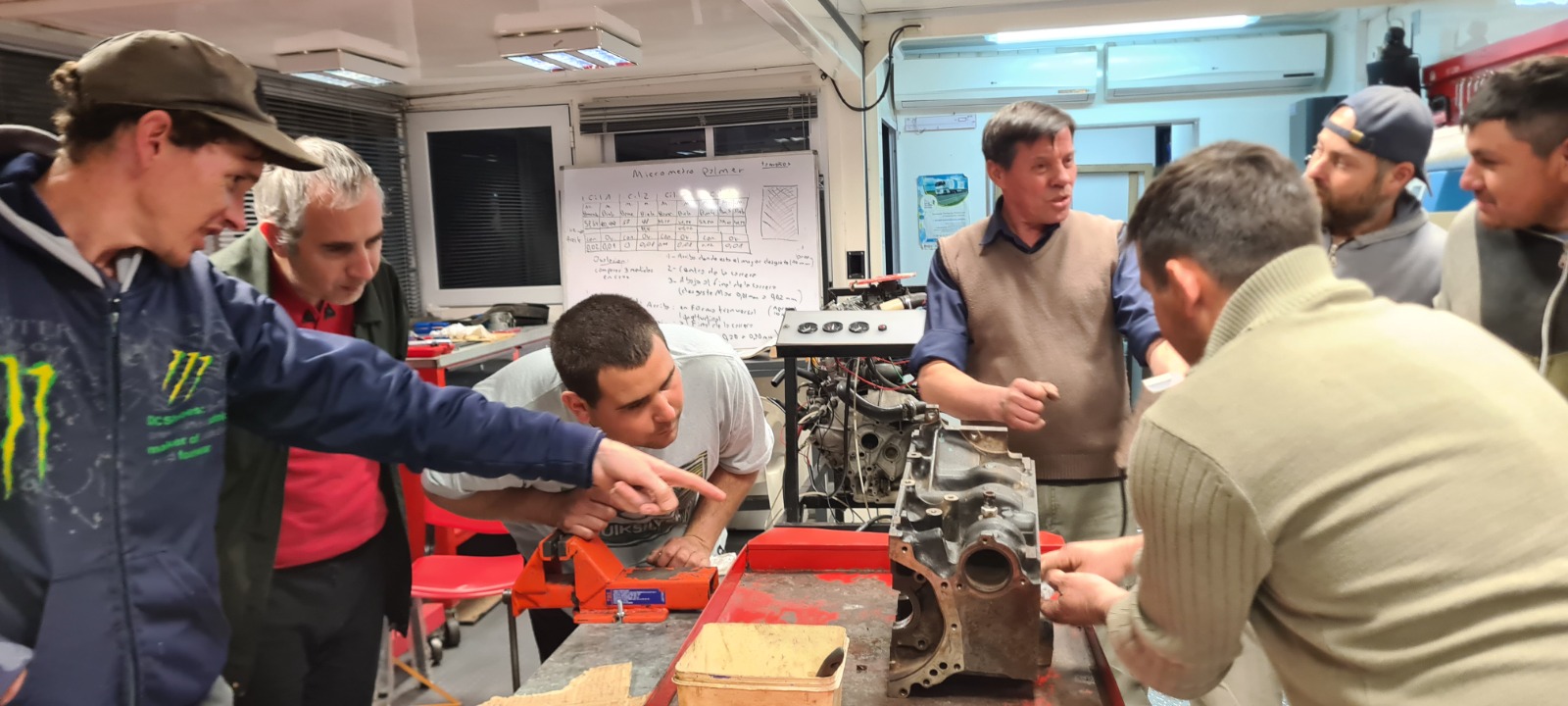 Alumnos y docente durante una clase práctica de mecánica automotriz